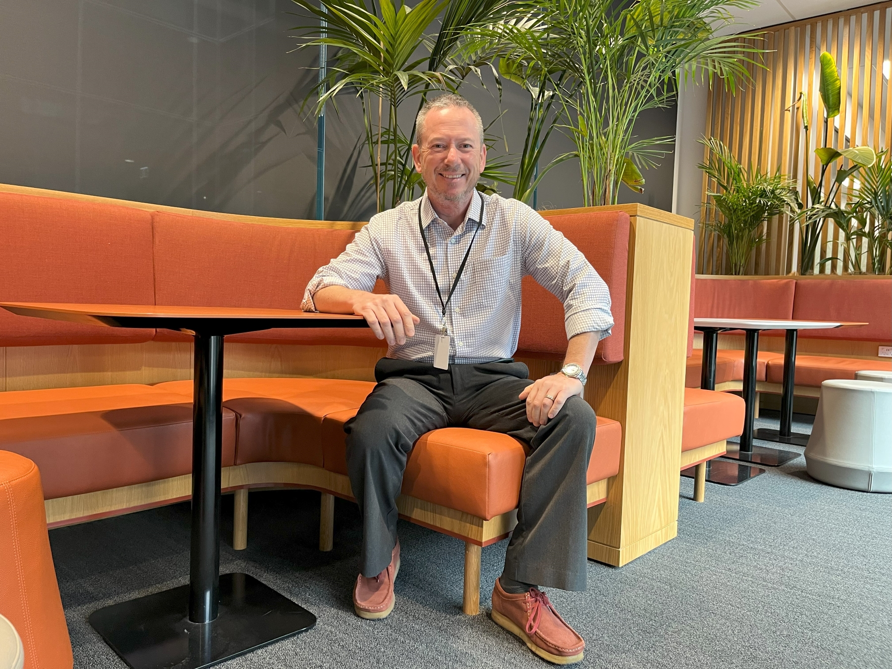 a man dressed in neat casual clothing sitting in a work office environment