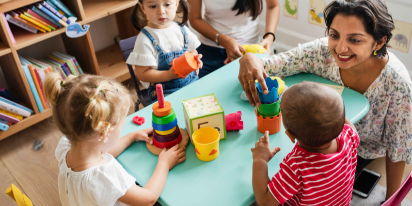 kids playing with toys, while sitting next to a day care worker