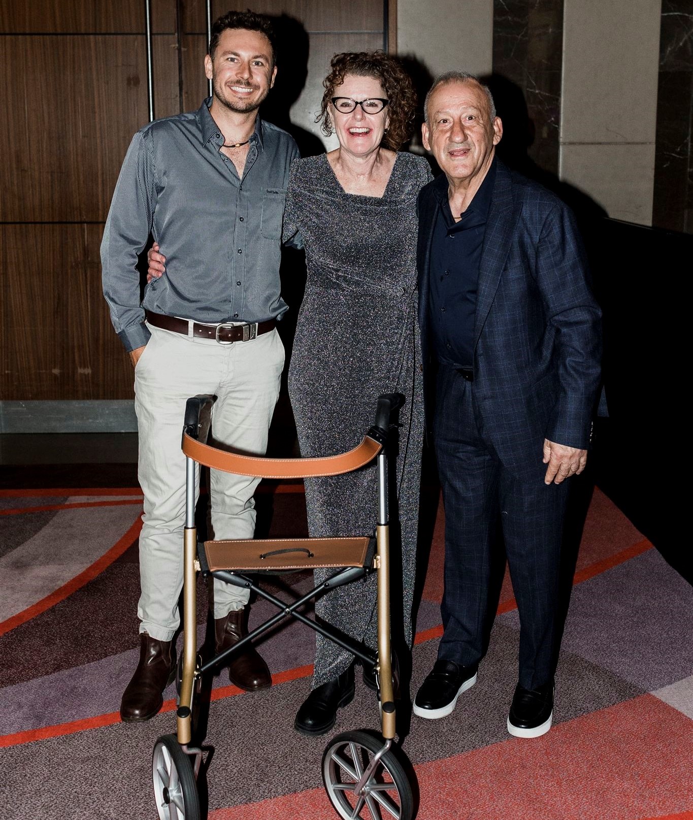 Two adult men and one adult woman, well dressed, smiling