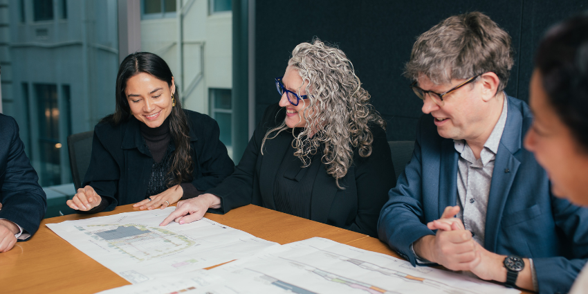 two women and one man viewing documents on a table and discussing it