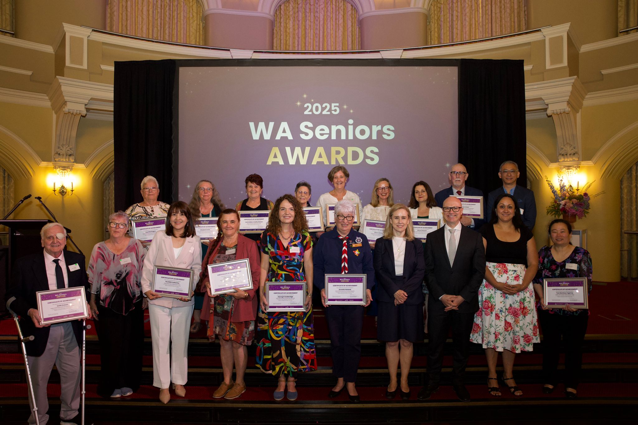 19 people on stage, 17 of which are award winners and finalists at the WA Seniors Awards 2025 ceremony. Also in the photo is the minister and Communities director general