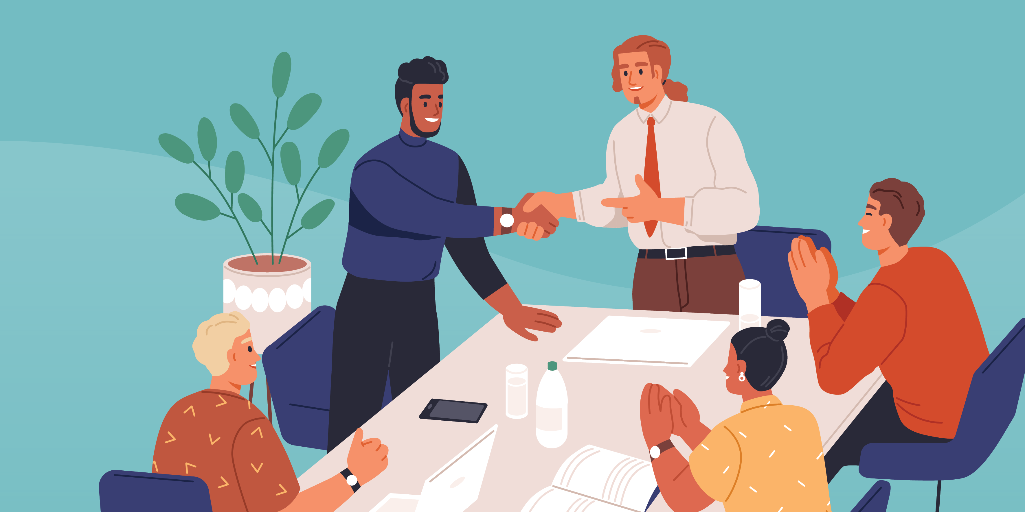 Group of people sitting around a table. Two people are shaking hands