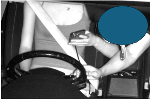 Driver using mobile phone while passenger holds the steering wheel