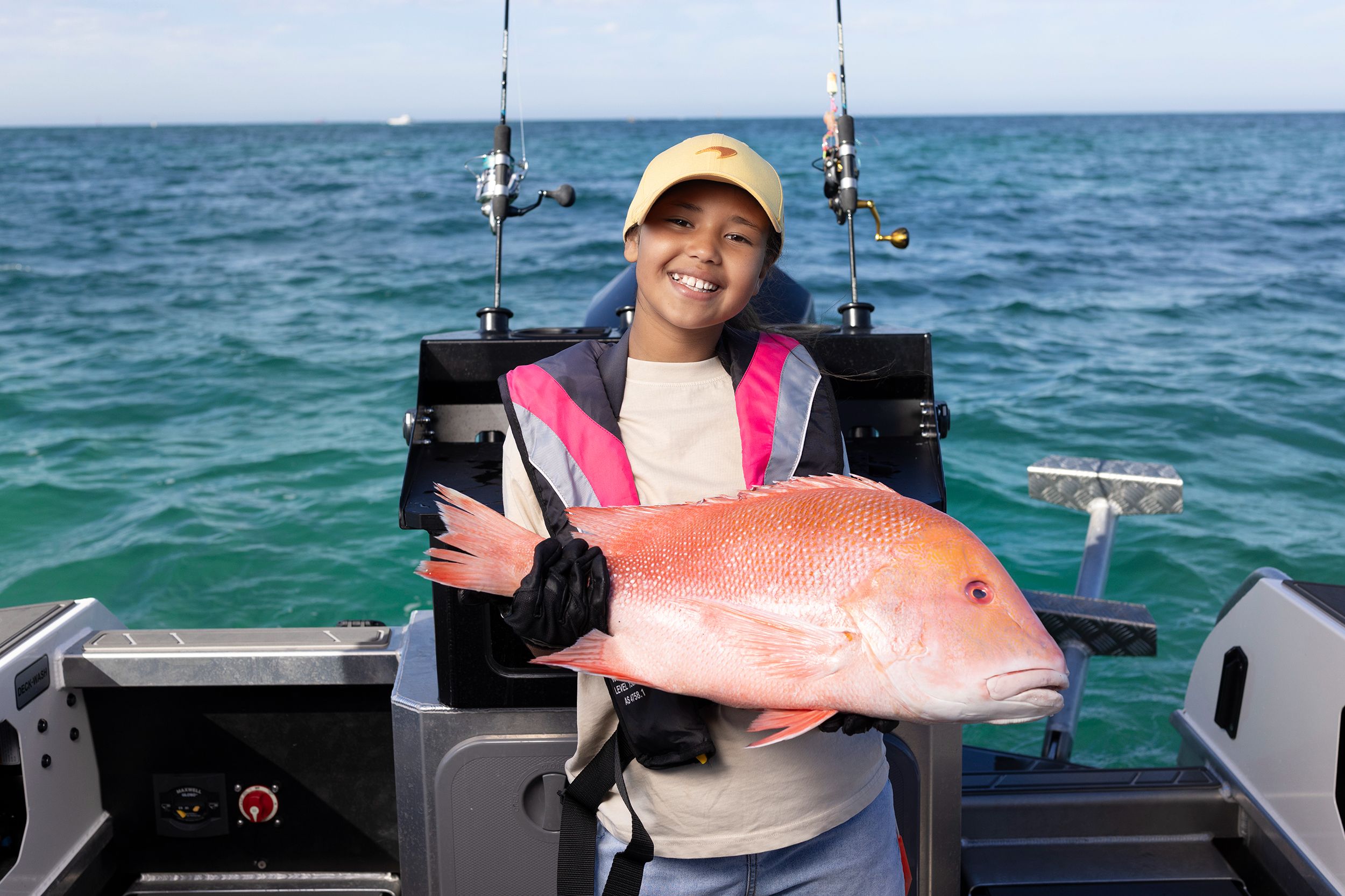 A young girl on a boat, holding a fish.