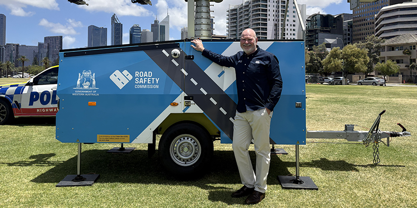 Road Safety Commissioner Adrian Warner standing in front of safety camera and police vehicles in Perth city