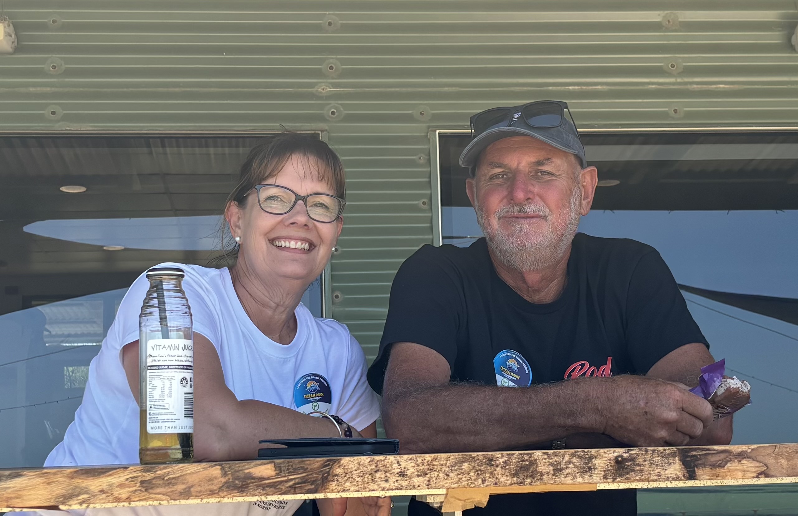 A man and woman sitting on a front verandah, smiling