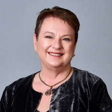 a woman, smiling, she has short hair and is wearing business attire. Head and shoulders pictured.