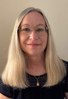 A woman wearing glasses, long hair, black top. Head and shoulders image