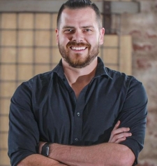 A man, smiling, arms folded. He has a beard.