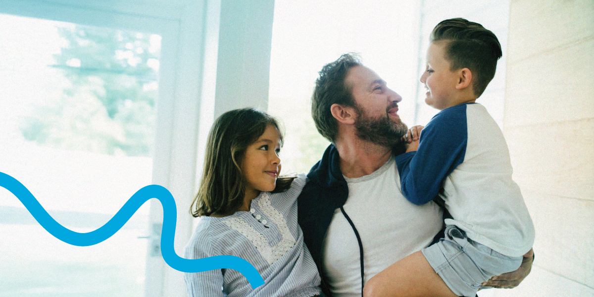 A dad holds his son and daughter in a pleasant home embrace