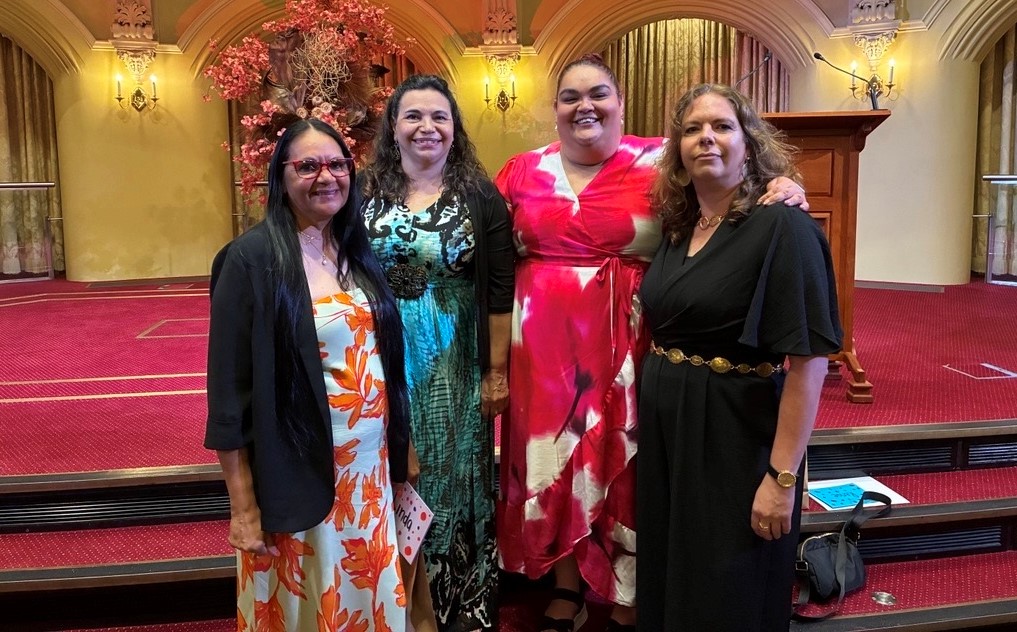 Four Aboriginal women, smiling, well dressed, in an indoor setting