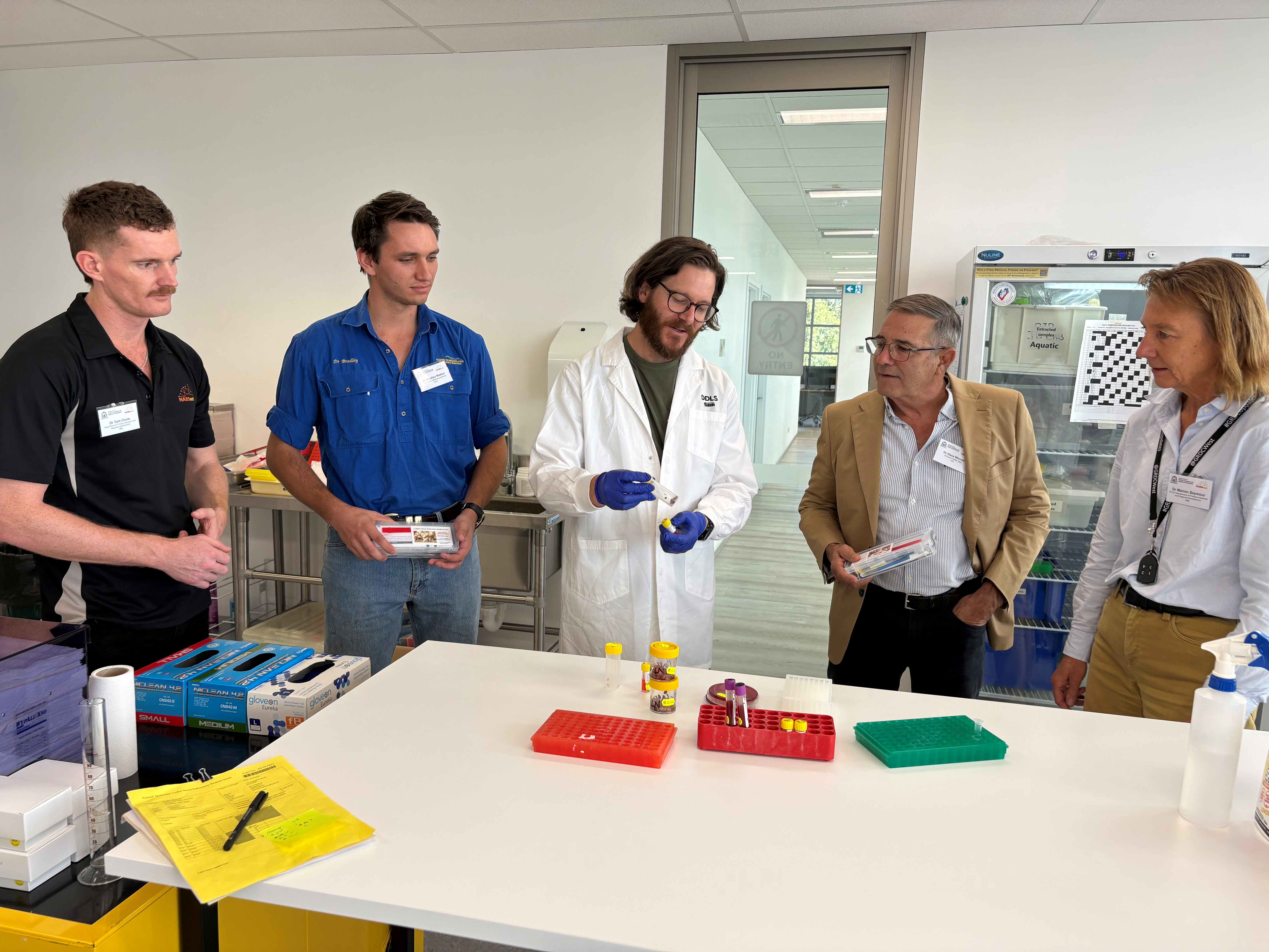 A group of people in a laboratory looking at a test tube.