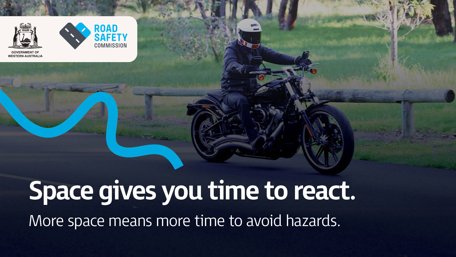 A motorcyclist riding next to a park with plenty of space around