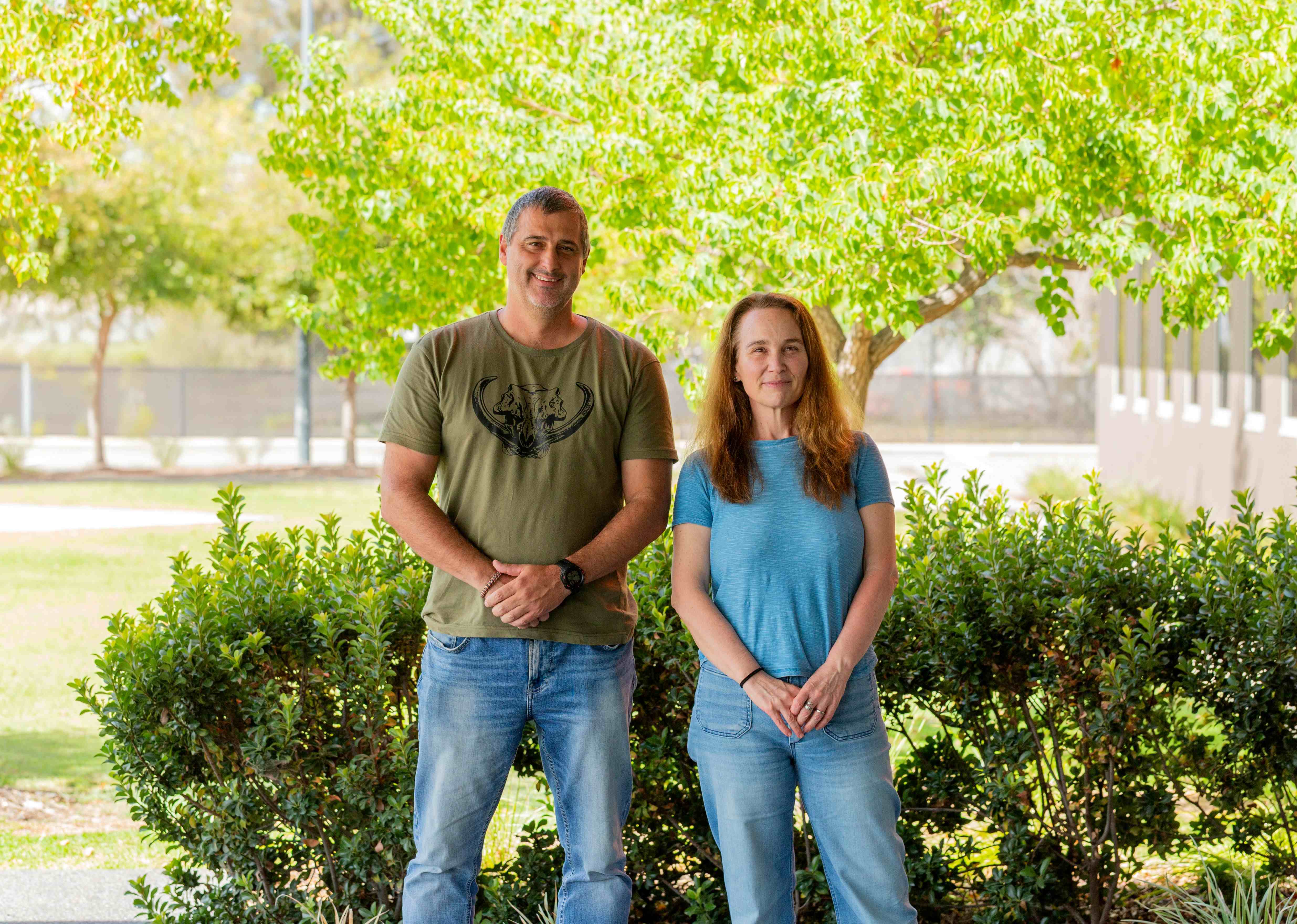 A man and a woman standing under a tree.