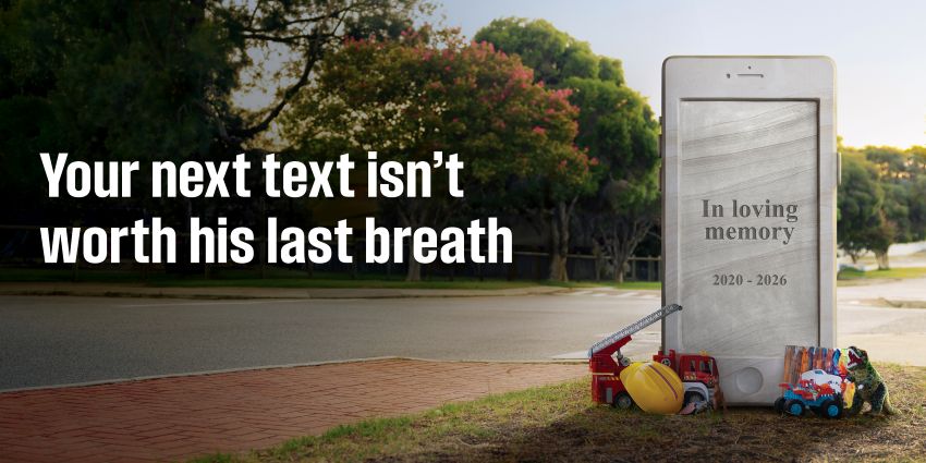 A headstone shaped like a phone on the side of a road. A child's belongings at the base.