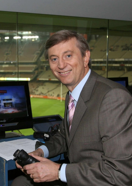 dennis cometti with a football oval in the background