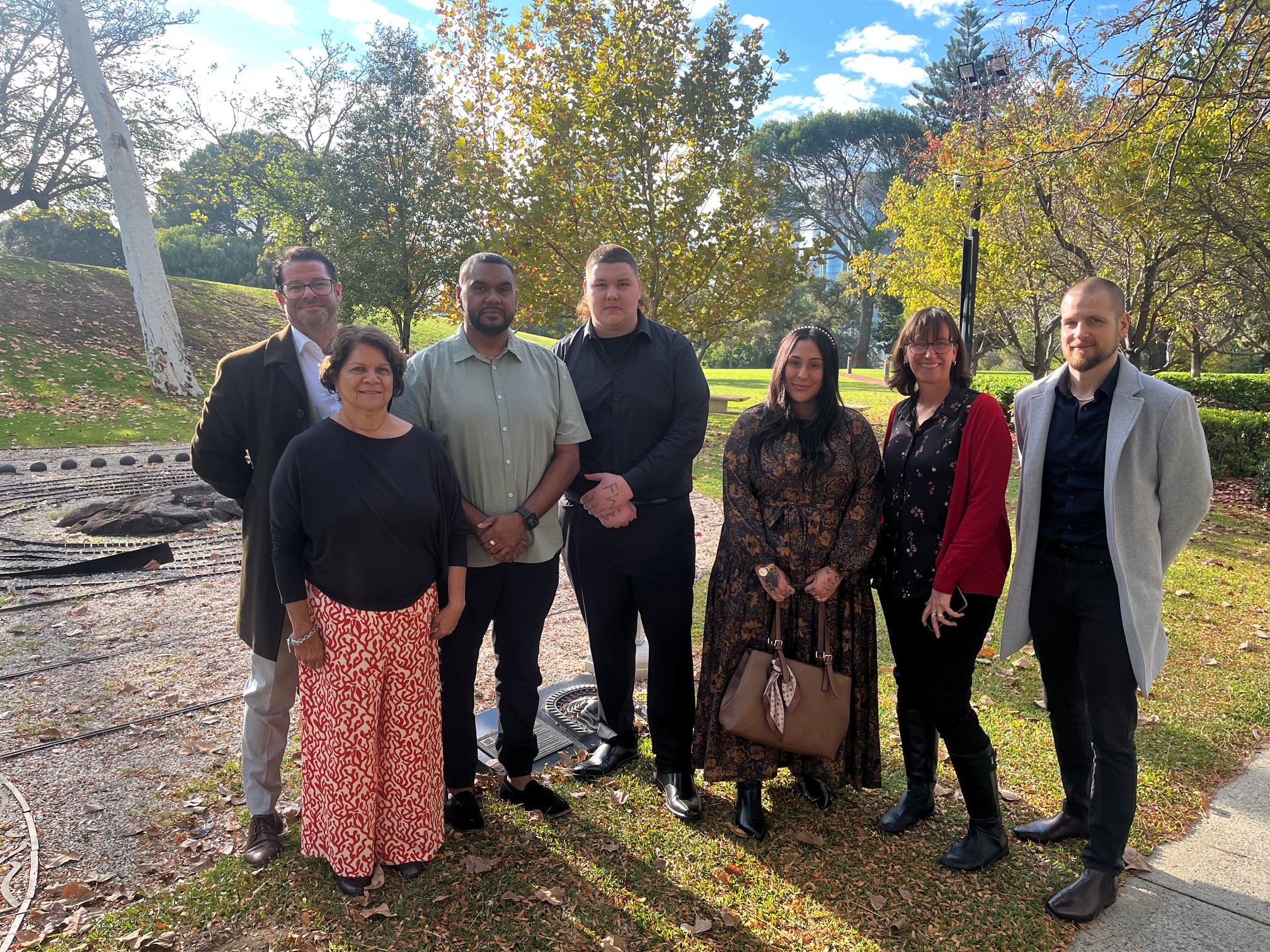 Group shot of seven neatly dressed adults in an outdoor setting