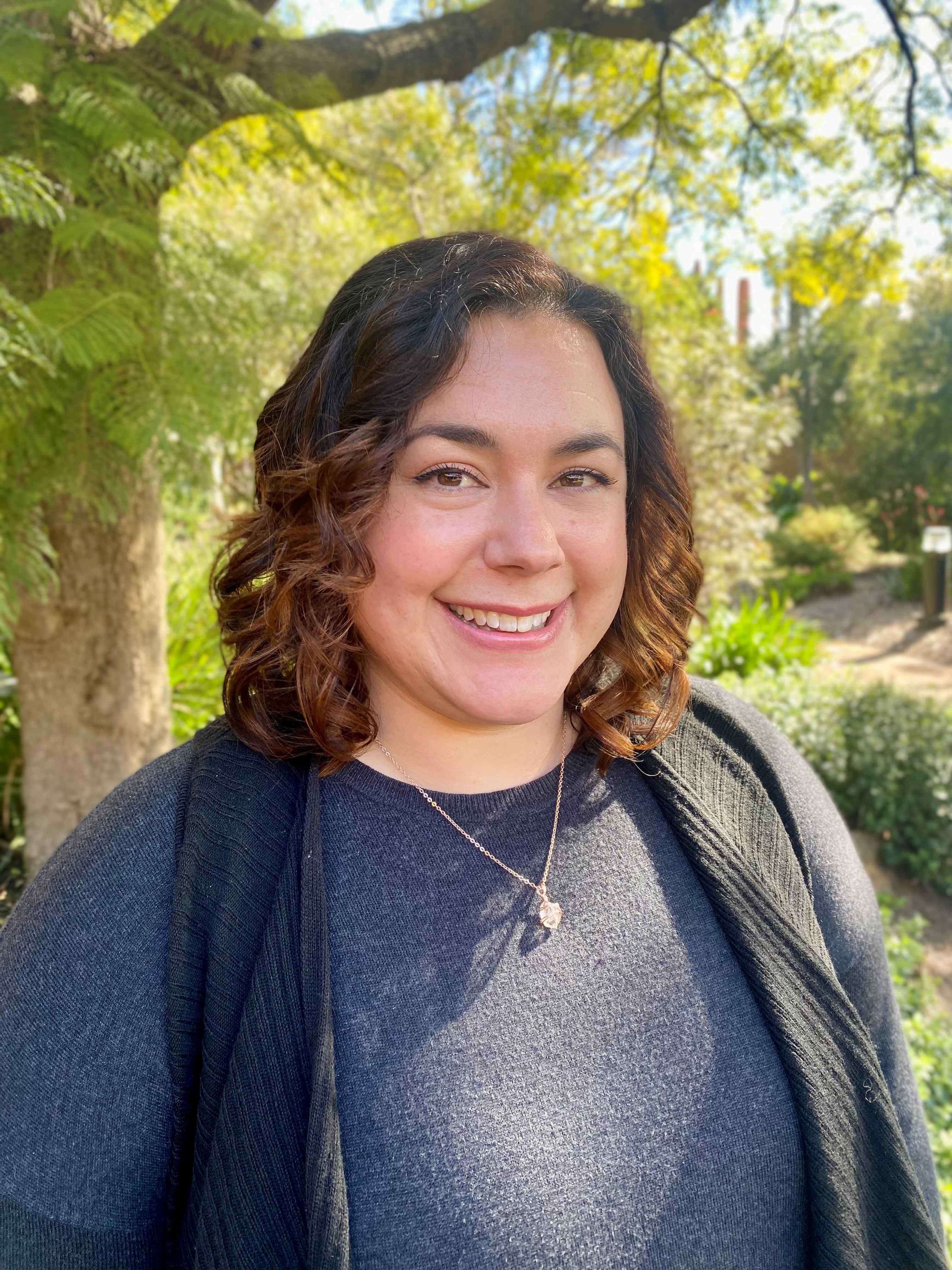 A headshot of a woman standing under a tree.