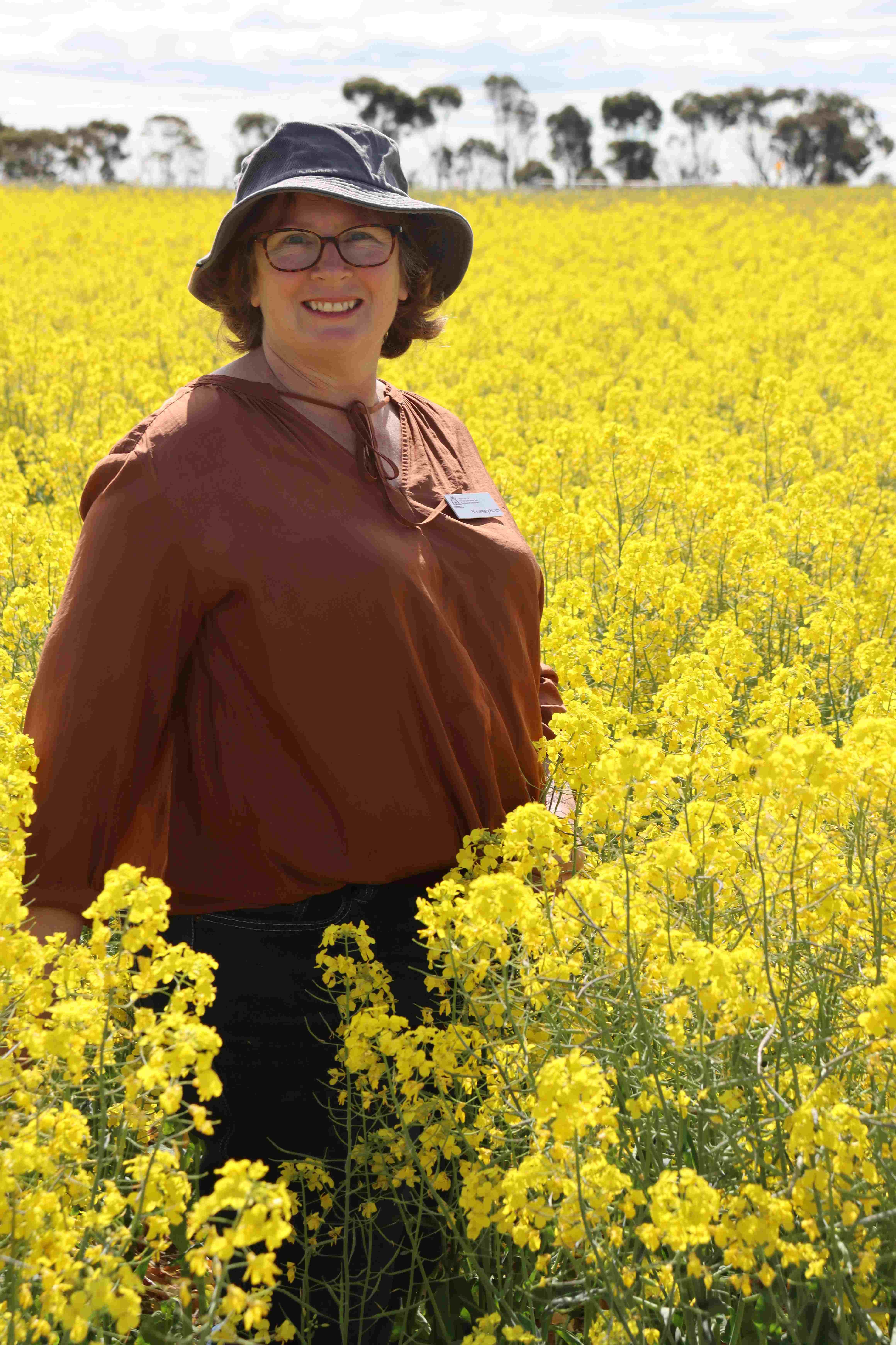 A soman standing in a crop of yellow flowering canola. 