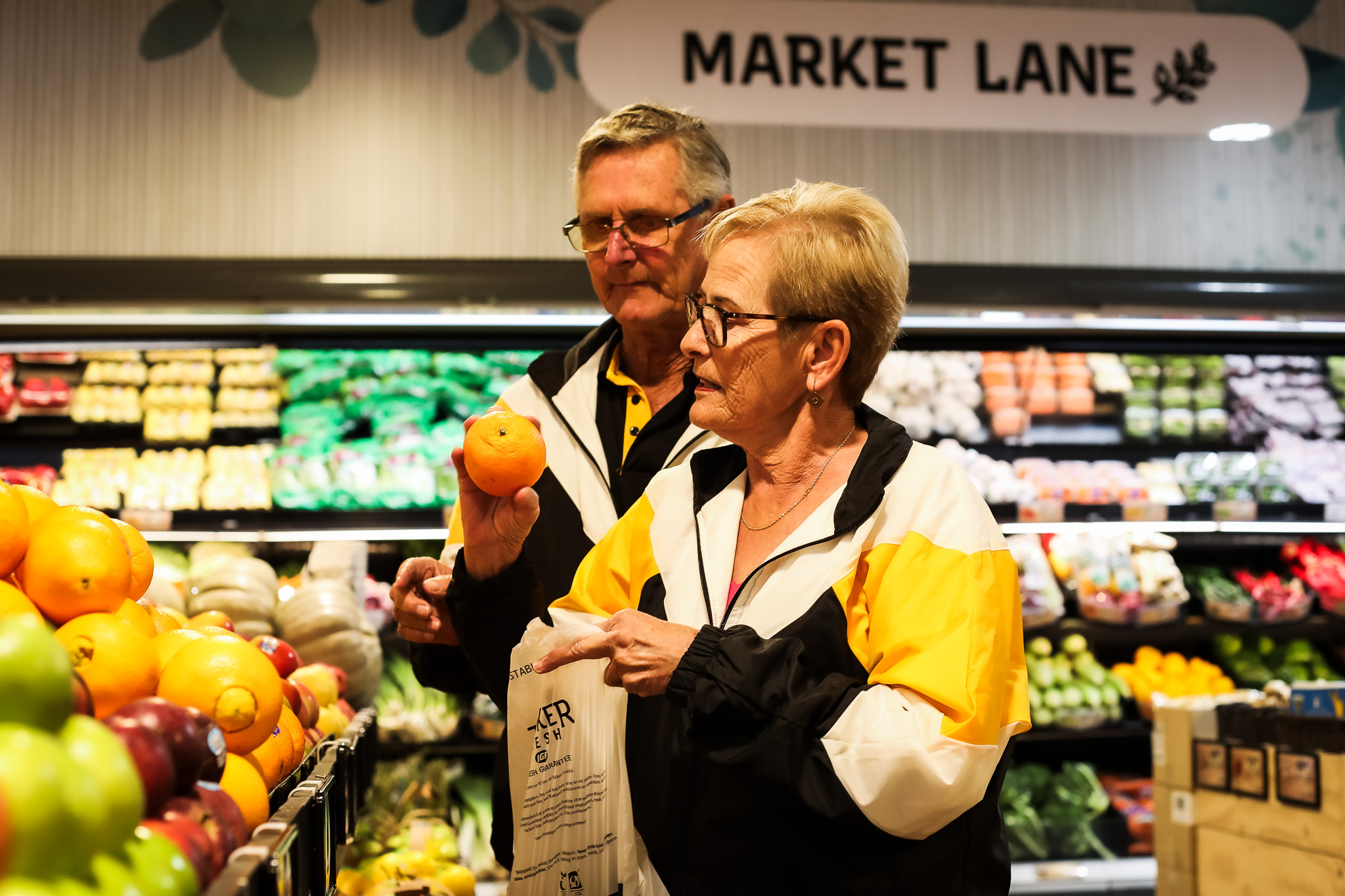 A middle aged couple shopping for fruit and vegetables in a grocery store
