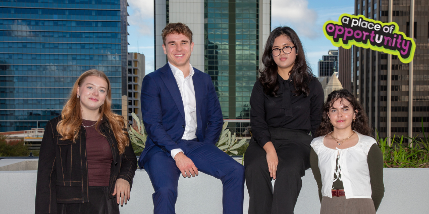 four young professionals with tall buildings in the background