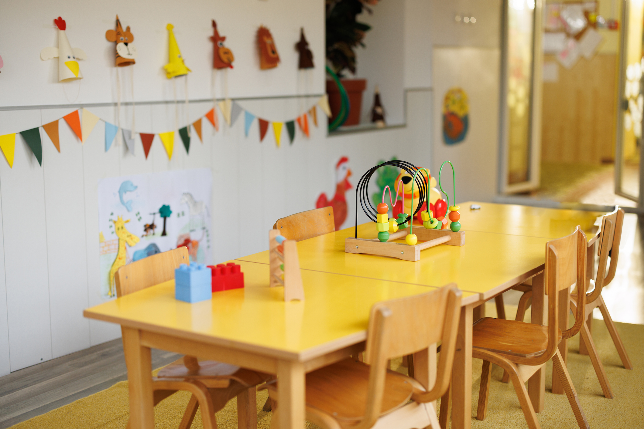 A timber table and chairs in an empty early learning centre room with learning toys on the table