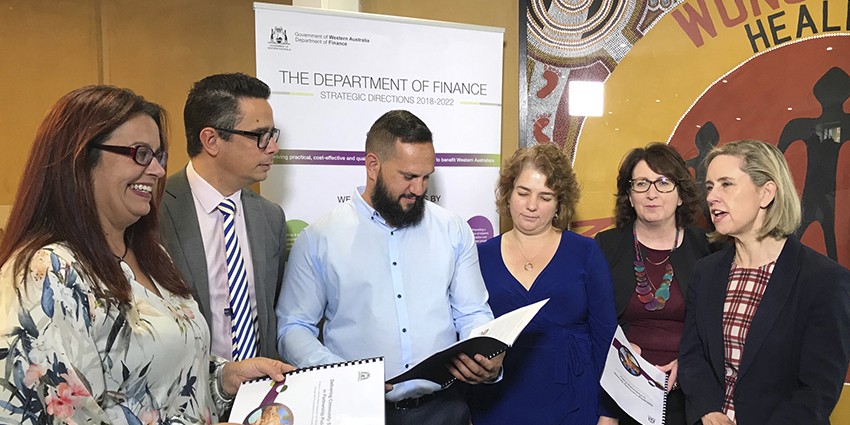 Six people reading community procurement documents infront of a Finance banner.