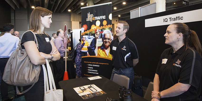 Two sales people from IQ Traffic talking with a customer at a trade expo
