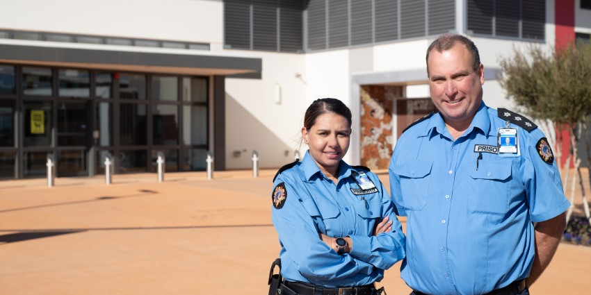 Two prison officers stand in front of Eastern Goldfields Regional Prison