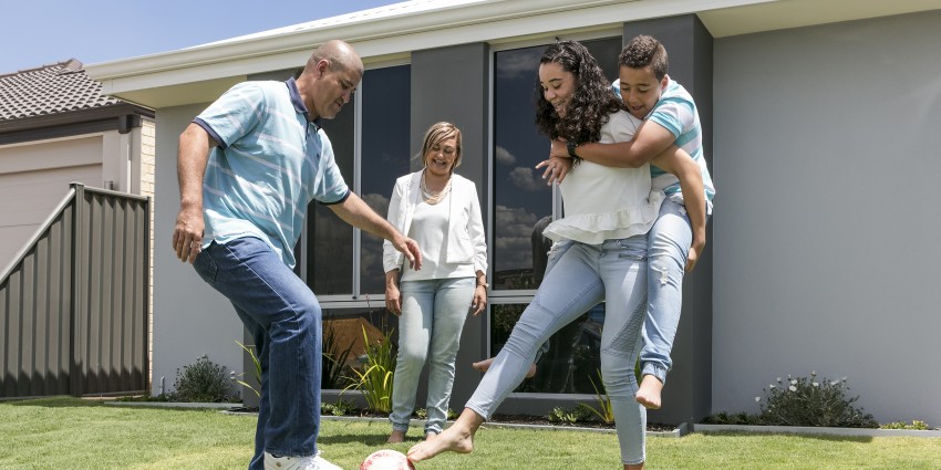 Photo of family kicking a soccer ball who have built a new house