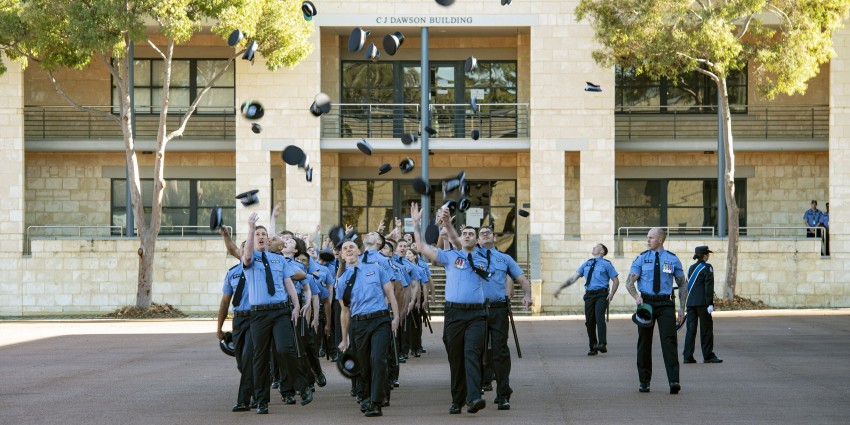 Police graduates throwing hats in the air