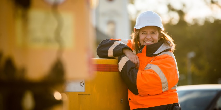 Woman builder at a construction site, wearing a hard hat and high visibility jacket.