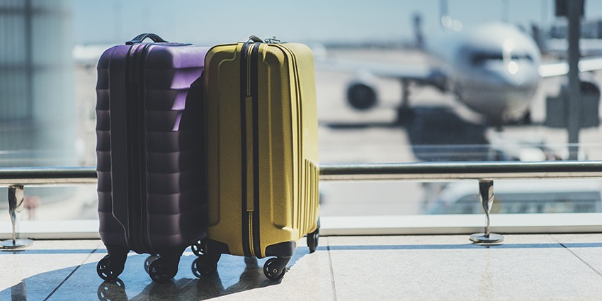 Two suitcases are lined up next to each other at an airport in front of an aeroplane.