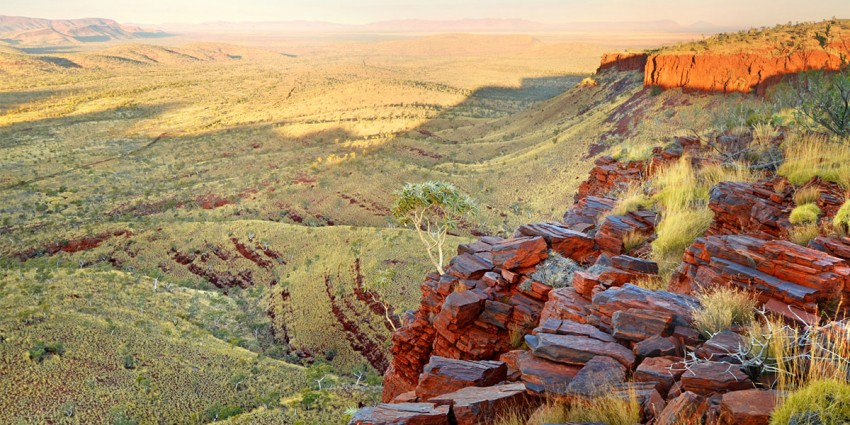 Landscape of north-west Western Australia. Featured are undulating grasslands and red rocks.
