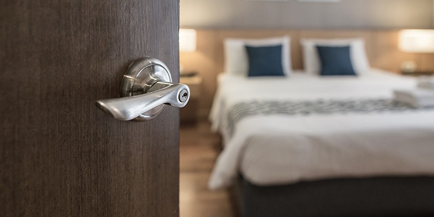 Image of a hotel room with a door handle in the foreground