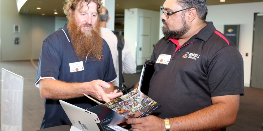 Two people discuss a brochure at an expo.