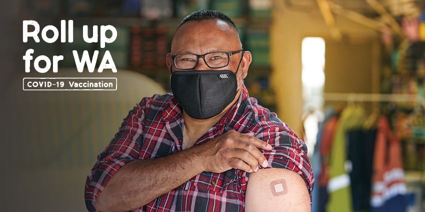 Photo of a man wearing a mask rolling up his sleeve to show he got vaccinated. The text next to him in the image says Roll up for WA COVID-19 vaccination.