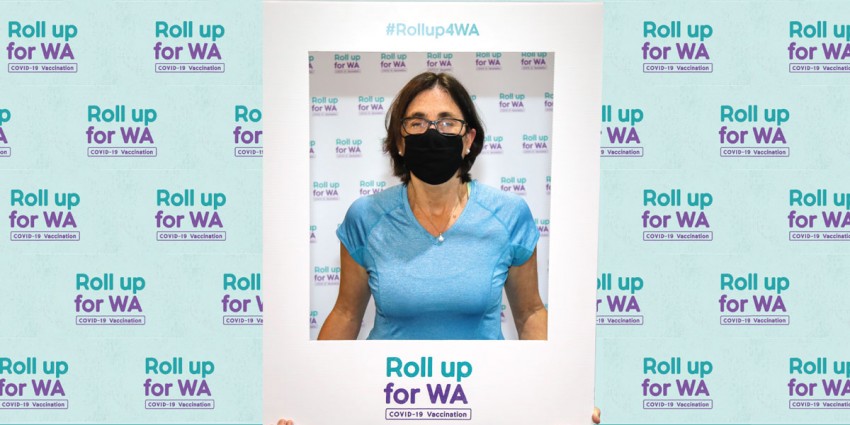 Department of Communities Director General Michelle Andrews standing in front of the "Roll up for WA" backdrop.