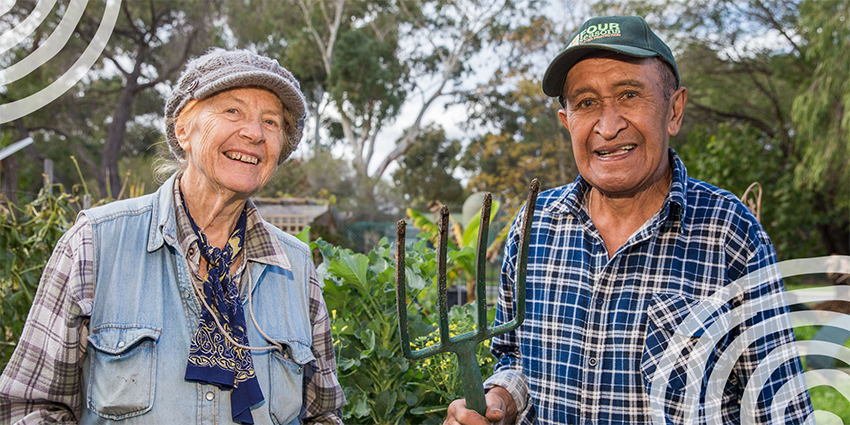 A senior couple smiling in their vegetable garden.