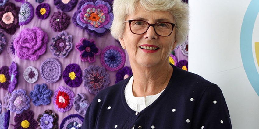 Judy Joukador standing in front of the Purple Road artwork.