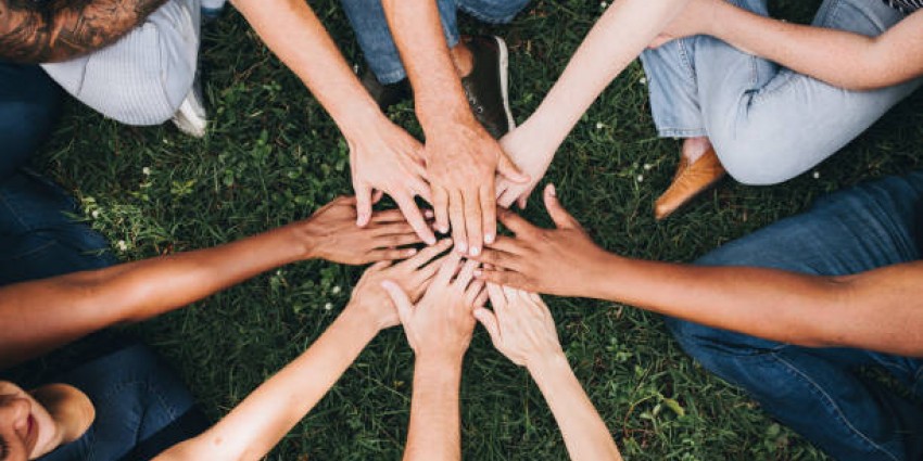 Community of people with their hands together in the centre of a circle