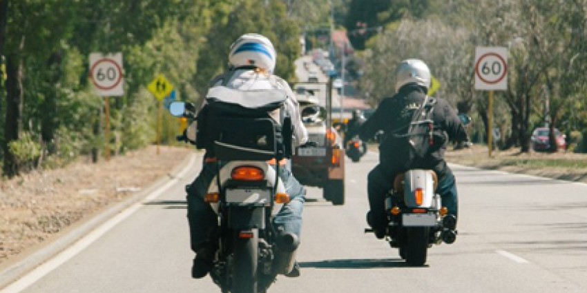 Two motorcyclists driving on a country road.