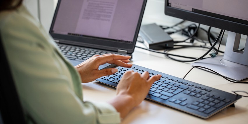 A person sitting in front of a computer, typing on the keyboard.
