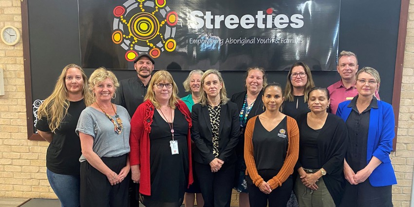 Image of Minister McGurk and stakeholders from Streetwork Aboriginal Corporation and Wungening Aboriginal Corporation. Streeties artwork in the background.