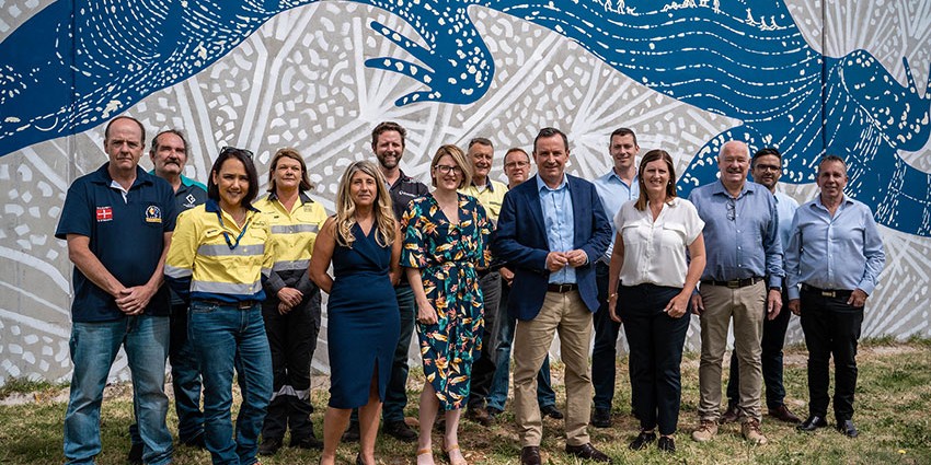 Premier Mark McGowan in front of a large mural Collie