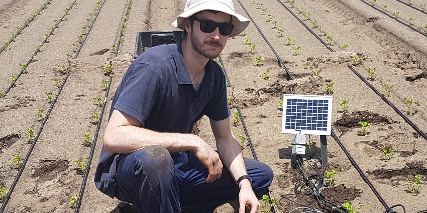David Rowe standing in crop with solar panel