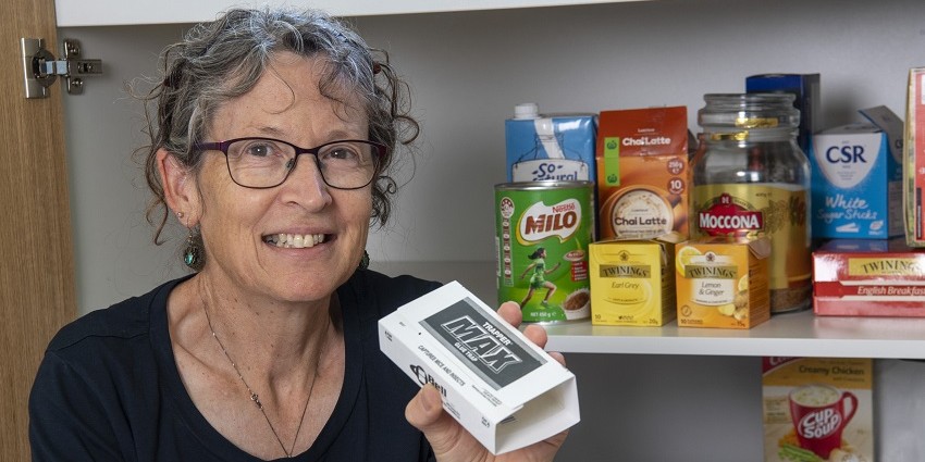 Woman standing in front of pantry holding a pest trap