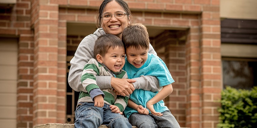 Image of Asian mum with her mixed race boys in front of their suburban home