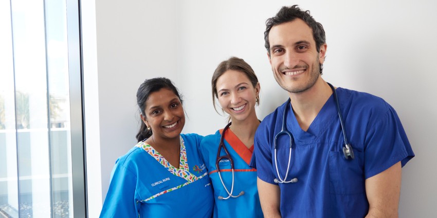 Three healthcare workers smiling at the camera