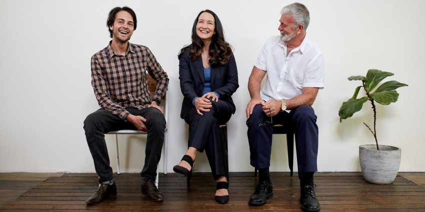 Image of three professional business people sitting in a row in a studio